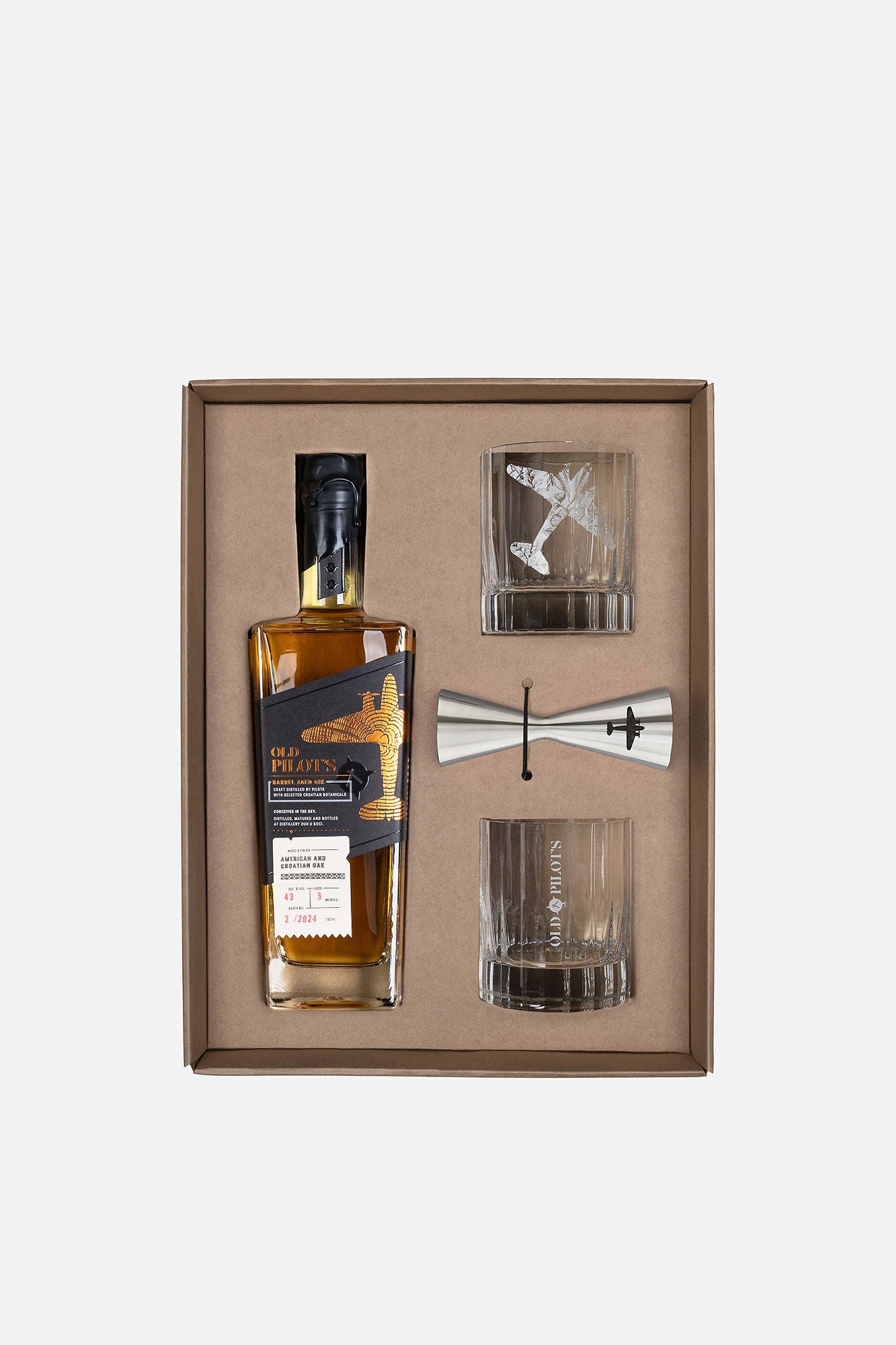 A whiskey gift set in a brown presentation box, featuring a bottle of Johnnie Walker Black Label whisky, a silver jigger, and two clear glasses, one with an airplane design.